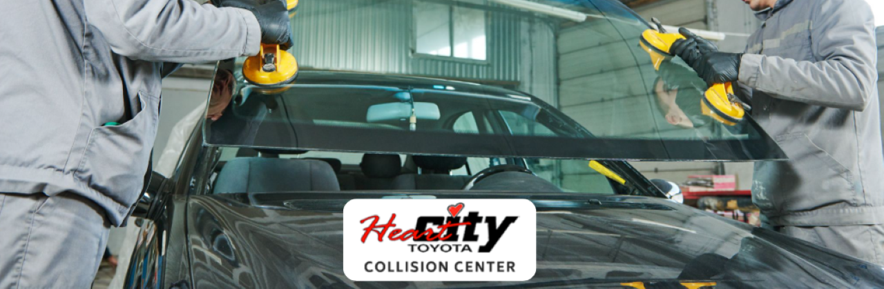 Technician repairing a car windshield using professional tools at Heart City Toyota Collision Center.