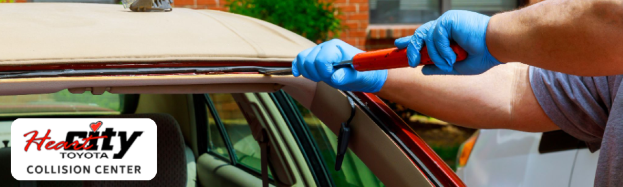Technician repairing a car windshield at Heart City Toyota Collision Center.